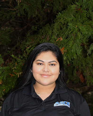 Karla Pineda standing outside at night time infront of a tree, wearing an ASCE shirt. 