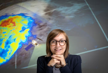 viviana maggioni in front of a weather map-like screen. 