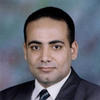 Amr El-Sayed wears a dark suit, white shirt, and striped tie